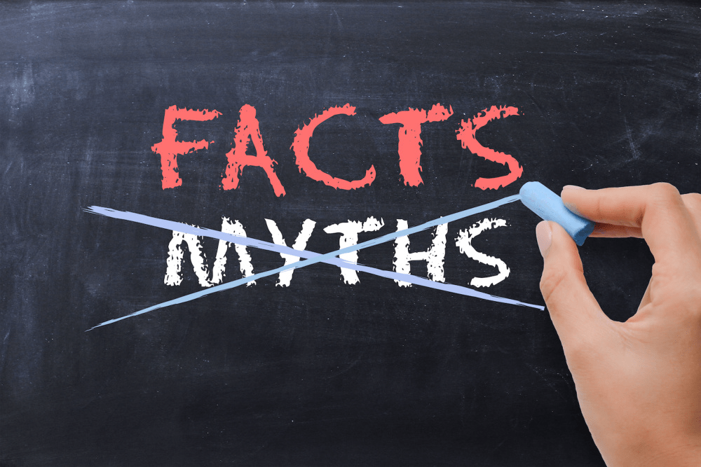 Hand crossing out the word myths and highlighting facts on a chalkboard, representing GPS tracking facts versus myths for businesses and fleets.