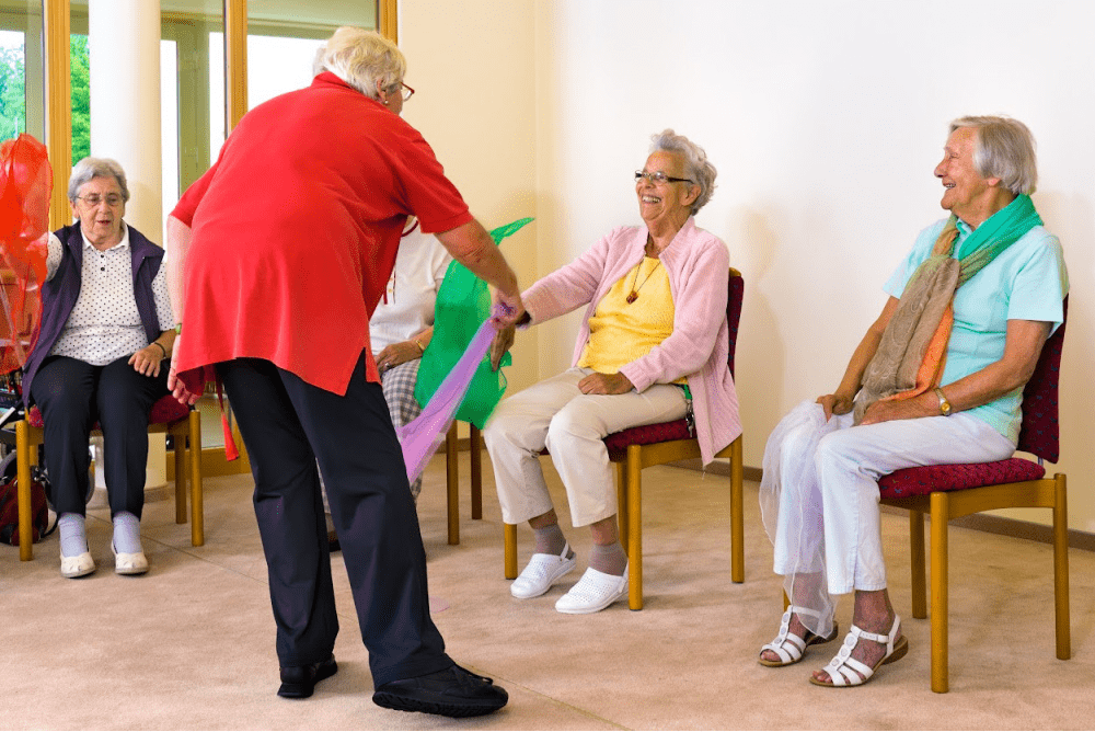 Group of elderly people participating in chair exercises at a senior care facility, representing GPS trackers for elderly care and personal safety.