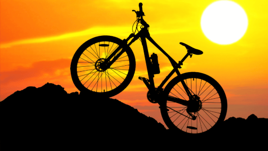 Silhouette of a mountain bike on a rocky hill at sunset, representing GPS tracking for bicycles and outdoor cycling security.