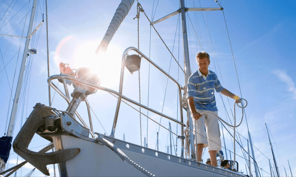 Man standing on a sailboat in sunlight, representing GPS boat tracking and marine fleet management solutions.