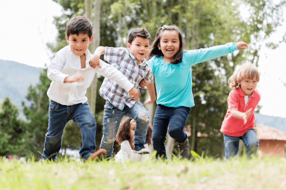 Group of happy children running and playing outdoors, representing GPS child trackers for safety and peace of mind.