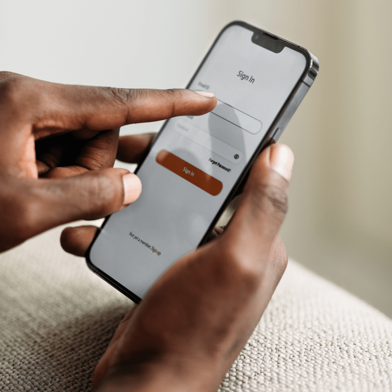 Person logging into a mobile app on smartphone screen, entering credentials on the sign-in page.