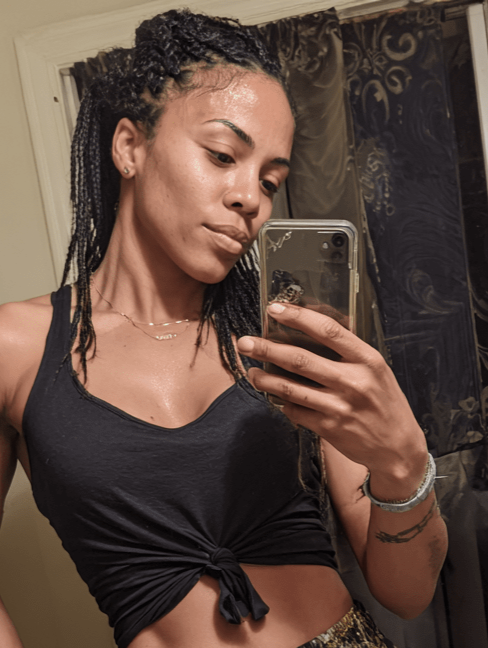 Person taking a mirror selfie wearing a black top and patterned shorts.