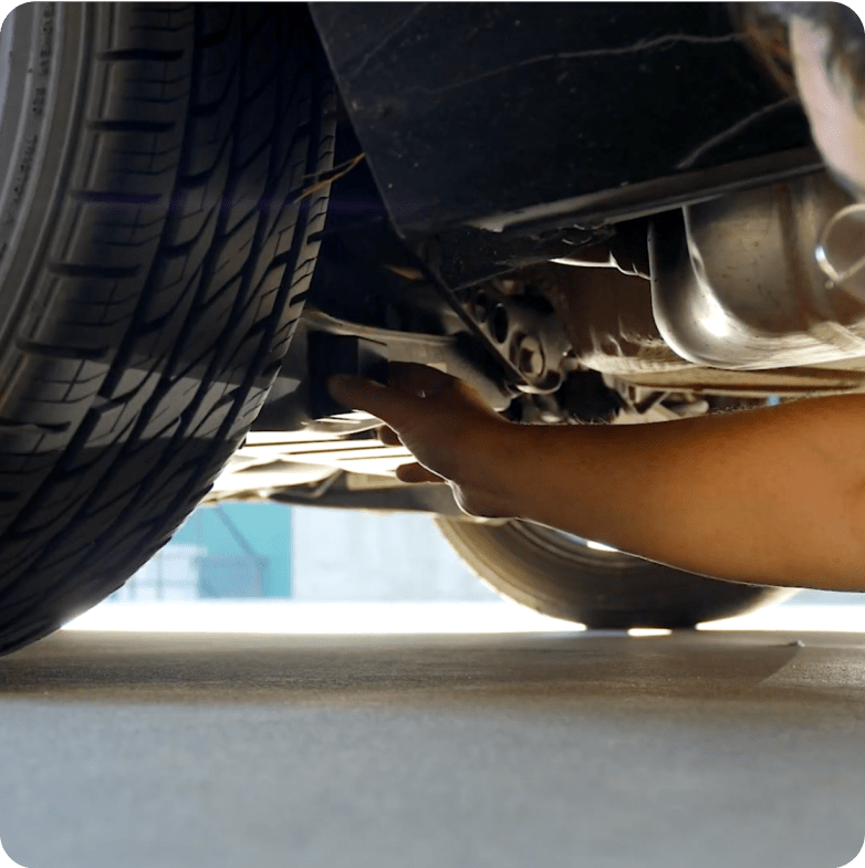 Person installing a magnetic GPS tracker under a vehicle for discreet real-time location tracking and theft prevention.