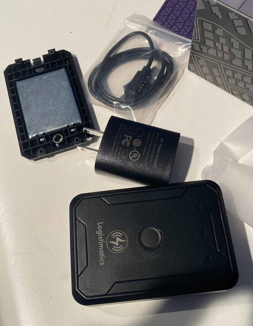 Gps device with audio listening functionality sitting on countertop with accessories.  