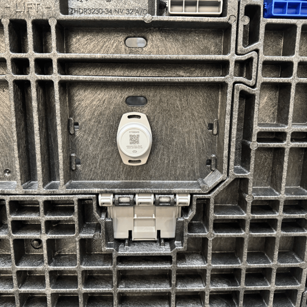Close-up of the textured dark gray plastic side panel of a utility crate, showing a circular white tracker with a QR code and molded structural ribs.