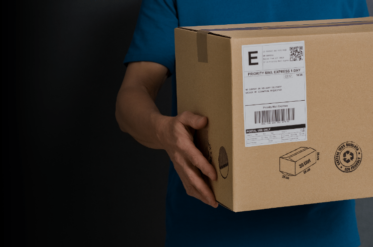 Delivery worker holding cardboard package with shipping label, representing parcel tracking and GPS shipment monitoring