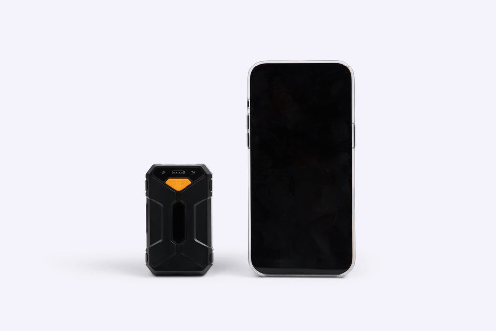 Small black tracker device next to a smartphone on a white background