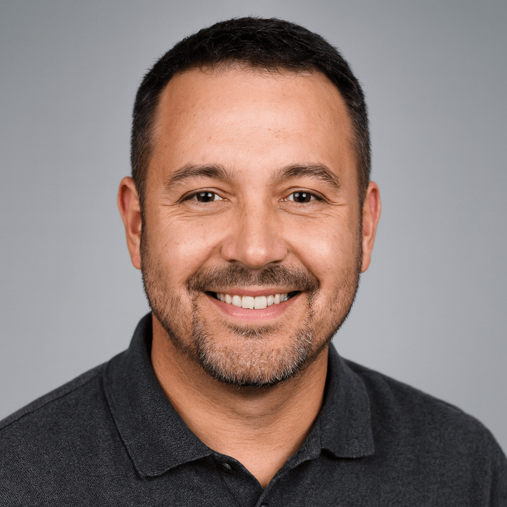 Man wearing a dark gray polo shirt against a gray background