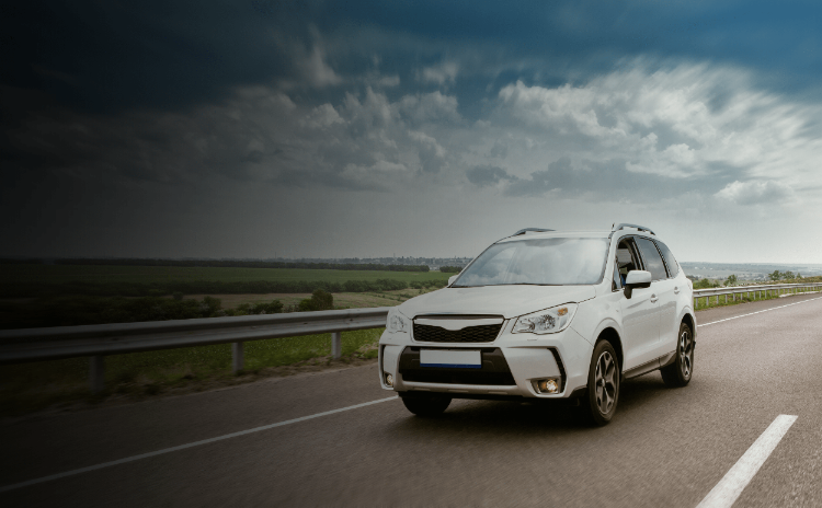 White SUV driving on highway under cloudy sky, representing GPS vehicle tracking, fleet monitoring, and driver safety solutions.