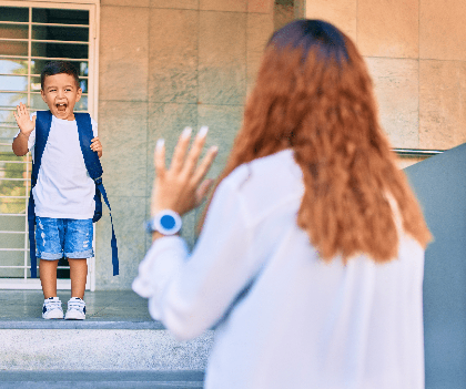 Young boy with a backpack waving goodbye to his parent, showing GPS tracking for child safety and peace of mind.