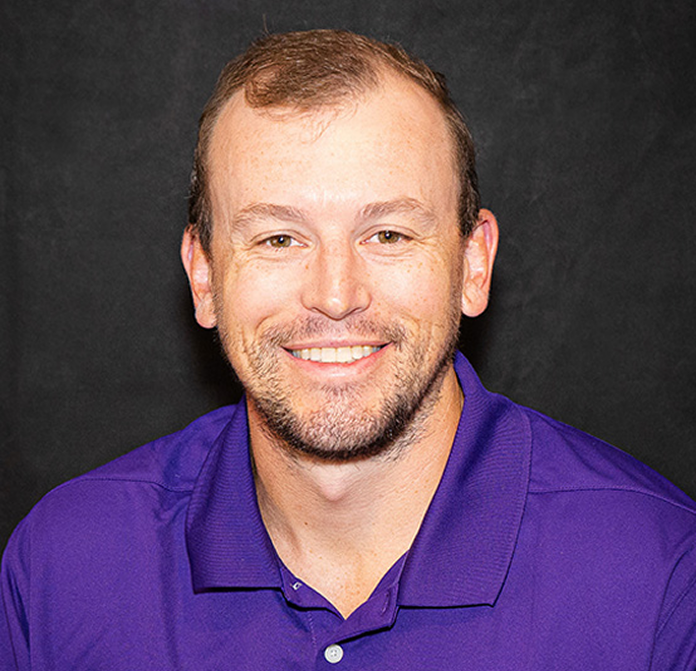 Man wearing a purple shirt against a black background